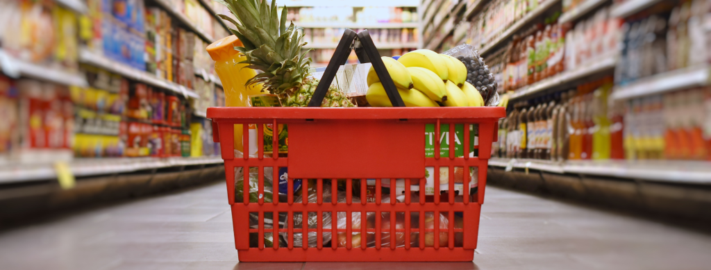 Basket of groceries sitting in a shopping isle.