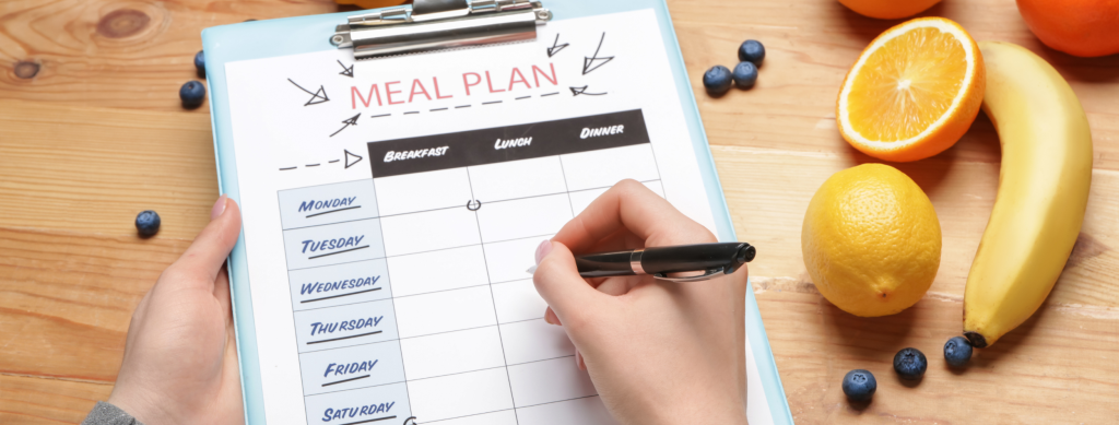 Simple meal plan template being held in hands with fruit placed on a table beside.