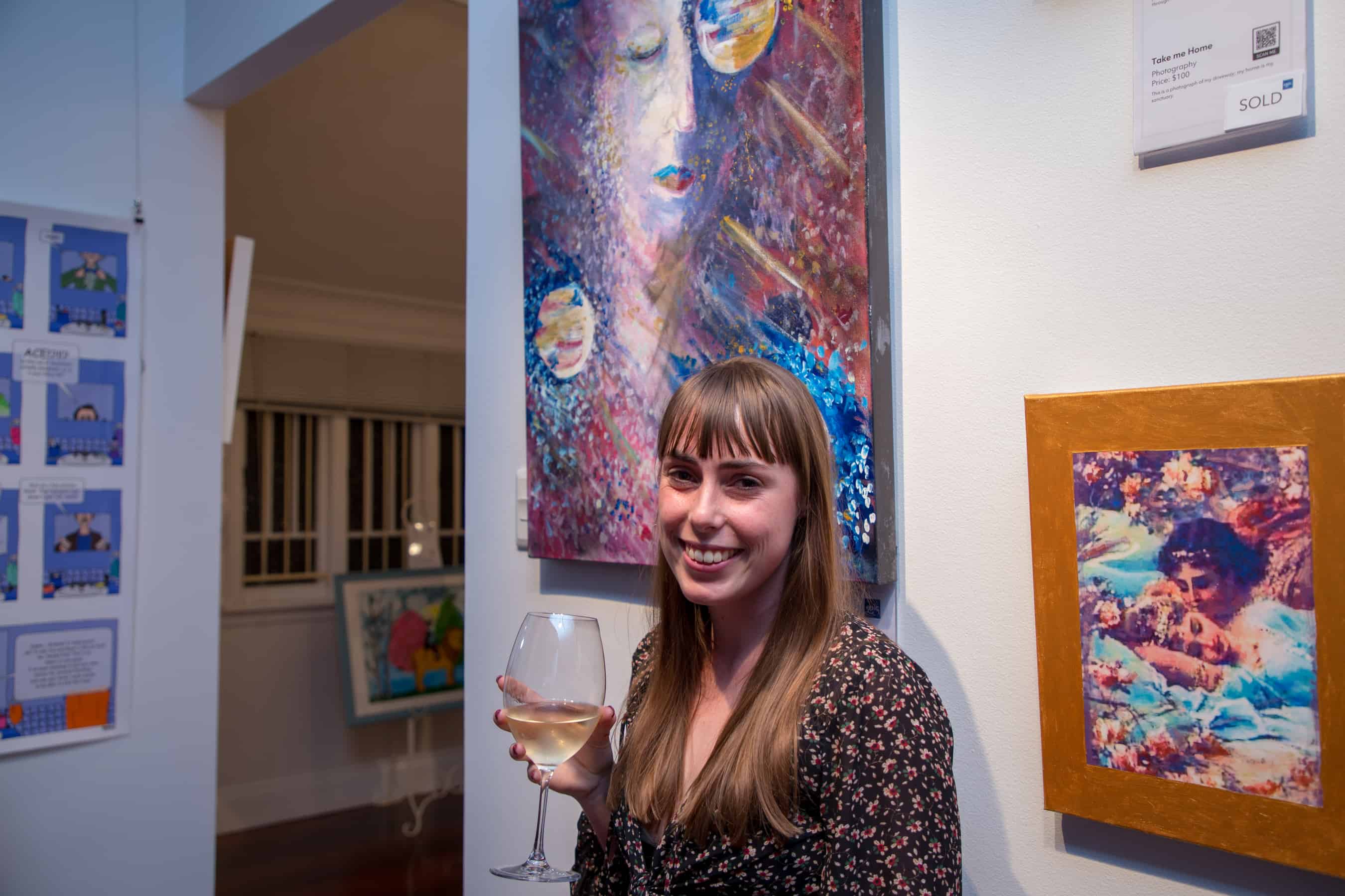 Artist Lily stands next to her painting