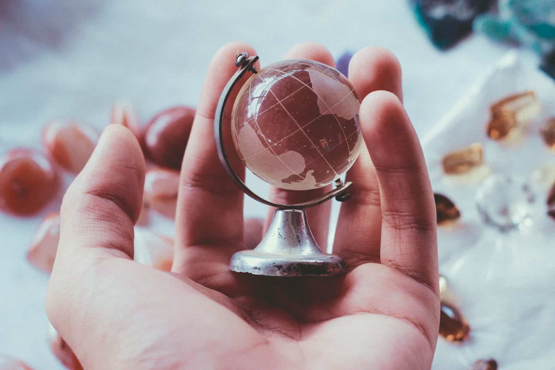 Close up of a hand holding a paperweight of a globe in their palm