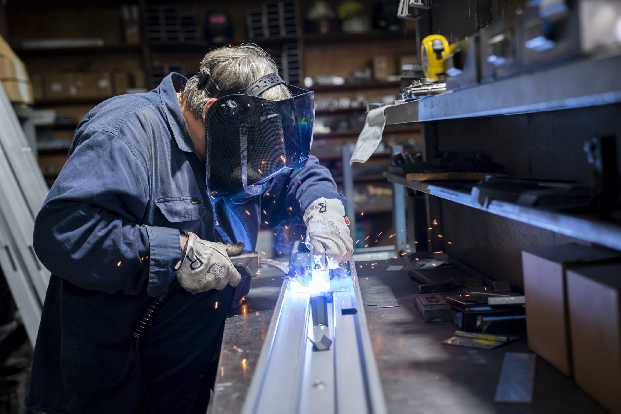 Sparks fly as Ron welds metal together.