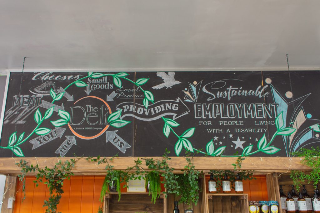 The Deli Cafe. Interior, chalk board with logo and green nature themed backdrop.