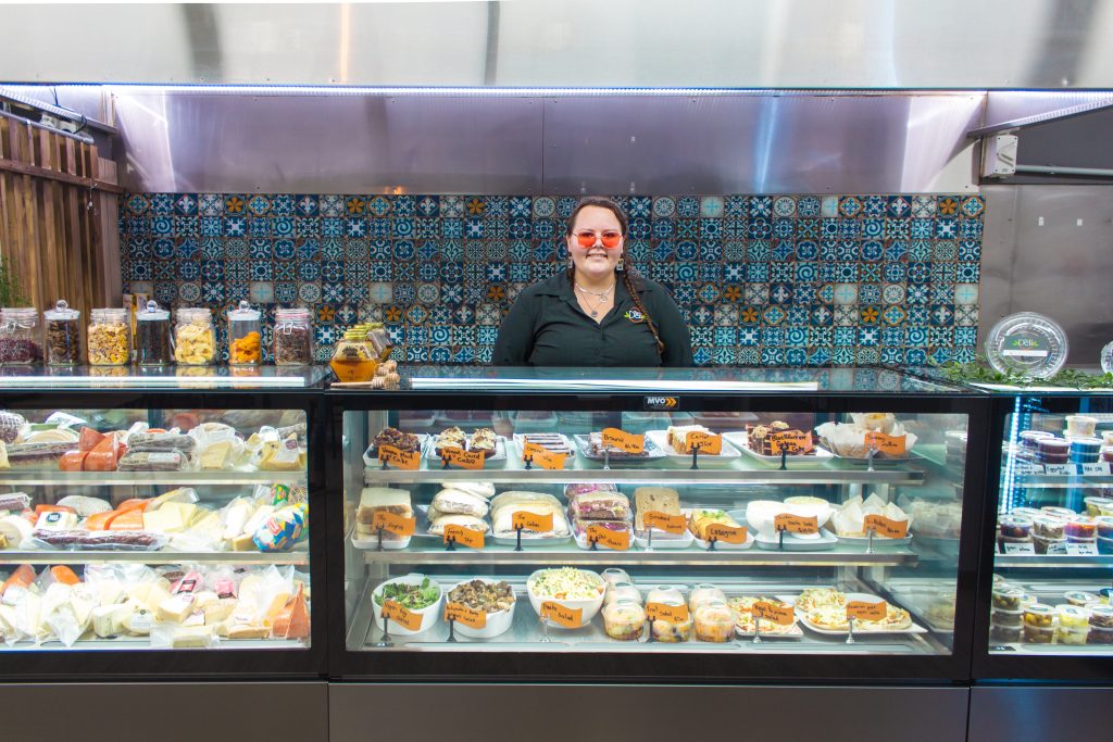 Gabrielle behind the counter at the Deli Cafe with a warm smile