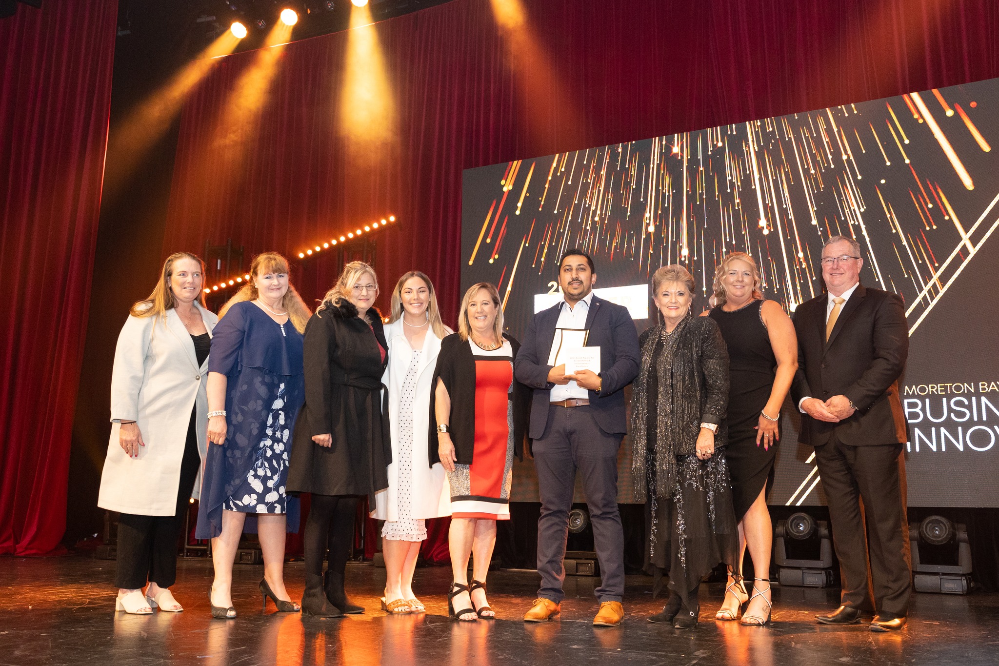 EPIC Operations Manager Jill Nash stands on stage at the 2023 MBRIT wards with winners Belgravia Leisure